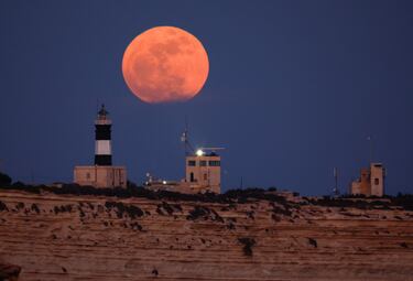 La luna llena se alza sobre el faro de Punta Delimara, vista desde Birzebbuga, Malta.