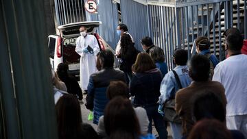 11 May 2020, Chile, Vina del Mar: A church cleric prays with family mmeembers and colleagues in front of the hearse carrying the body of a civil servant during his funeral after he died from coronavirus at the Carlos Van Buren Hospital. Photo: Miguel Moya/Agencia Uno/dpa
 
 
 11/05/2020 ONLY FOR USE IN SPAIN