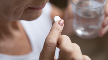 Una mujer tomándose una pastilla