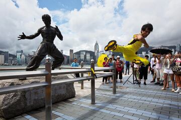 El actor chino Mei Zhiyong realiza una patada voladora frente a una estatua de bronce de Bruce Lee en la Avenida de las Estrellas, en Tsim Sha Tsui (Hong Kong). Un buen número de curiosos se reunió para conmemorar el
50 aniversario de la muerte de la superestrella televisiva y leyenda del kung fu, fallecido el 20 de julio de 1973