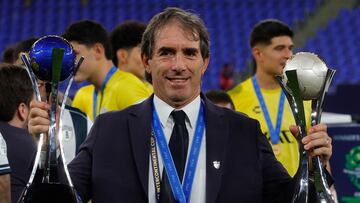 Pachuca's Uruguayan manager Guillermo Almada poses for a picture with the trophies after the 2024 FIFA Intercontinental Cup football match between Mexico's Pachuca and Egypt's Al-Ahly at Stadium 974 in Doha on December 14, 2024. (Photo by KARIM JAAFAR / AFP)