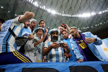  Los hinchas argentinos estuvieron muy pendientes de todo lo que ocurría en el Education City entre Croacia y Brasil. Como este grupo de aficionados albicelestes, quienes siguen a través de un teléfono móvil, en las gradas del estadio de Lusail, la tanda de penaltis entre ambas selecciones antes del comienzo del Países Bajos-Argentina. 