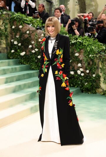 Anna Wintour,  la organizadora de la Met Gala, posa con un vestido blanco y abrigo negro con flores de colores bordadas.