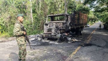 A Colombian soldier stands guard next to a burnt truck in Taraza Municipality, Cauca, Colombia, on March 20, 2023. - Colombian President Gustavo Petro ordered, on March 19, 2023, the resumption of offensive actions against the Clan del Golfo, Colombia's largest drug gang, for attacks on civilians and the security forces, which led him to suspend the ceasefire. (Photo by Eder Narvaez / AFP) (Photo by EDER NARVAEZ/AFP via Getty Images)