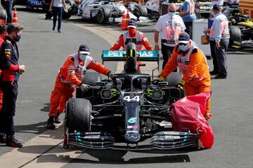 Los operarios mueven el monoplaza del Lewis Hamilton con la rueda dañada.