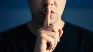 Secret and silence. Quiet silent shh gesture with finger on lips. Man doing expression with hand on mouth. Taboo topic, censorship or freedom or speech. Conspiracy theory. Confidential talk.