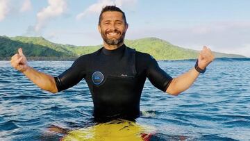 El ex jugador de f&uacute;tbol campe&oacute;n del mundo y de Europa, Bixente Lizarazu, esperando las olas sobre su tabla de surf amarilla y con su neopreno Quiksilver, haciendo el gesto surfista del shaka. 