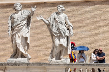 Fieles y un guardia suizo se encuentran cerca de estatuas durante la misa inaugural del Papa León XIV en la Plaza de San Pedro.