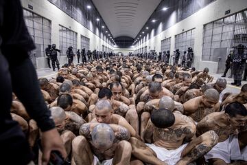 Pasillos del Centro de Confinamiento del Terrorismo, lleno de pandilleros esposados en el suelo mientras esperan a ser llevados a su celda.