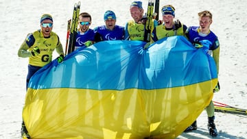 Los ucranianos Anatolii Kovalevskyi y su gu&iacute;a Oleksandr Mukshyn, Vitalii Lukianenko y su gu&iacute;a Borys Babar, y Dmytro Suiarko y su gu&iacute;a Oleksandr Nikonovych posan con la bandera de Ucrania tras ganar el bronce, el oro y la plata en biatl&oacute;n en los Juegos Paral&iacute;mpicos de Invierno de Pek&iacute;n 2022.