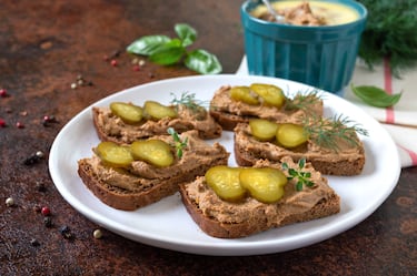 Unta paté de hígado de pollo sobre rebanadas de pan de centeno, coloca rodajas finas de pepinillo encurtido y sirve como aperitivo elegante y lleno de sabor.