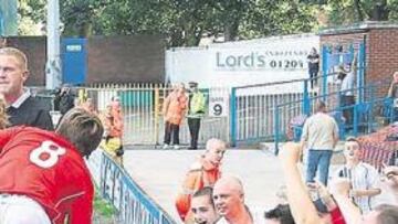 <b>SALVADORES DE ALMAS ABIERTOS AL AFICIONADO.</b> Sobre estas líneas, dos aficionadas en los vestuarios del equipo: el club facilita el contacto entre socios y jugadores hasta durante los partidos. A la derecha, dos pancartas de seguidores del FC United: en la superior se puede leer: No tengo que vender mi alma. En la inferior, Canción de amor en la Décima División.