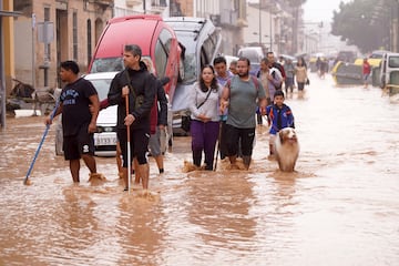 Un grupo de personas caminan por calles inundadas en Valencia, España.