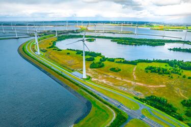 Enorme sistema de islas artificiales y tierras utilizadas como barreras naturales para contener el agua, cubiertas con aerogeneradores y una carretera que conecta al continente en Países Bajos. 
