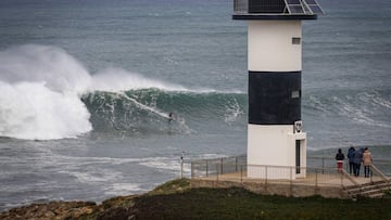 Un surfista surfeando una ola de izquierdas en Illa Pancha, con el faro en primer plano. 