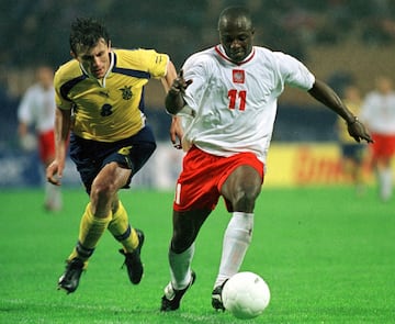 El delantero nigeriano, internacional con Polonia, tuvo un año espectacular en Panathinaikos ganando todo lo posible en Grecia y llevando con sus goles a Polonia al mundial que se disputaría en 2002.