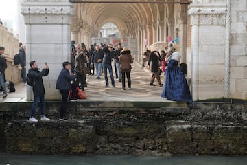 Turistas toman fotografías durante una fuerte marea baja en la ciudad laguna de Venecia, Italia.