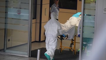 Un sanitario protegido con un traje y guantes de látex, empuja una camilla con una persona sobre ella en el Hospital Universitario Cruces, uno de los hospitales públicos vascos de referencia para infectados por coronavirus, 19 de marzo de 2020.
