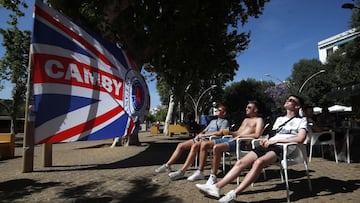 Aficionados del Rangers toman el sol en una calle del centro de Sevilla.