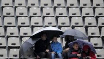 Espectadores se protegen de la lluvia bajo los paraguas después de que los partidos del torneo de Roland Garros hayan sido aplazados por la lluvia.