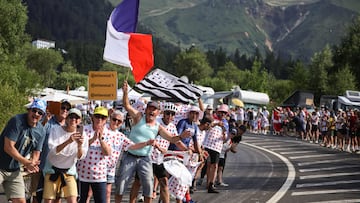 spectators wave a French flag in the final ascent of the 10th stage of the 112th edition of the Tour de France cycling race, 165.3 km between Ennezat and Le Mont-Dore Puy de Sancy, in central France, on July 14, 2025. (Photo by Anne-Christine POUJOULAT / AFP)