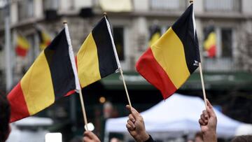 People wave Belgian flags as they observe a minute of silence