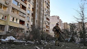 A member of the Ukrainian Territorial Defence Forces walks near a damaged apartment block after it was hit by debris from a downed rocket in Kyiv on March 17, 2022, as Russian forces press in on the Ukrainian capital.