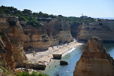 Una extensa pero suave escalera nos permite acceder a una pequeña ensenada. A medida que avanza hasta la línea del acantilado, el visitante se topa con un arenal que se extiende hacia el oeste. Acantilados calizos de tonos calientes, muy fracturados y con fisuras, rodean la playa y exhiben una notable diversidad de curiosos modelados rocosos: arcos, grutas, peñascos y simas. 