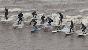 Surfers ride the Severn Bore surge wave, a natural phenomenon occurring according to the lunar cycle where a set of waves push through the Severn River estuary and upstream on a high tide, on the only day in 2024 where it is given a five star size status, at Newnham, near Gloucester in Britain, March 12, 2024. REUTERS/Toby Melville