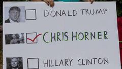 Una votante en las elecciones de Estados Unidos posa con una pancarta en la que aparecen los candidatos Hillary Clinton y Donald Trump y el ciclista Chris Horner.