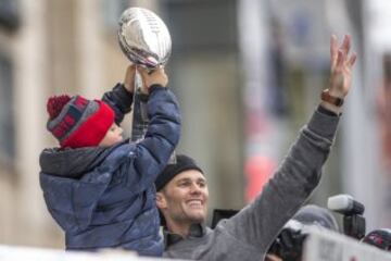 Tom Brady levanta a su hijo Benjamin que alza el trofeo Vince Lombardi durante el desfile de la victoria de los Patriots.