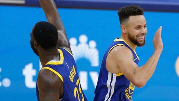 Stephen Curry y Draymond Green se saludan tras una acción en un partido.