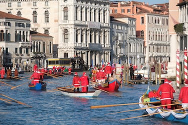 Personas vestidas de Papá Noel reman durantela  regata navideña en el Gran Canal de Venecia.