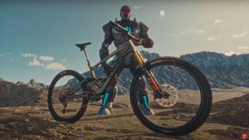 La e-MTB Specialized Turbo Kenevo SL en primer plano, con el monstruo el&eacute;ctrico vinculado a la bici que salva el planeta detr&aacute;s y monta&ntilde;as nevadas al fondo. 