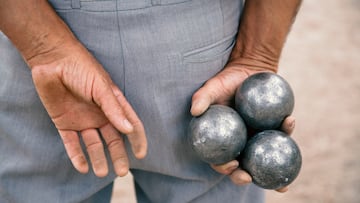 Older man holding boules for game.
