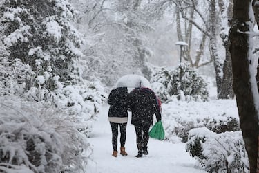 Dos personas caminan por la nieve en Madrid.