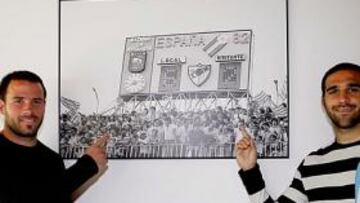 <b>ESTANDARTES. </b>Apoño y Gámez en un posado de archivo de AS junto a la fotografía que retrataba el 6-2 del Málaga al Real Madrid.