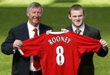 Wayne Rooney levanta la camiseta del club con el entrenador Sir Alex Ferguson en el campo en Old Trafford tras su fichaje por el Manchester United.