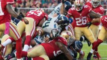 Marshawn Lynch mantiene el balón en una pila de jugadores de los 49ers.