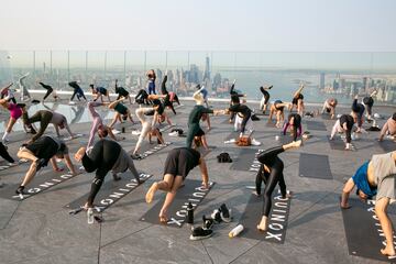 Un grupo de personas hace yoga en la azotea de un edificio de Manhattan (Nueva York). Como ocurre con muchos tipos de ejercicios al aire libre, esta práctica cogió gran demanda durante la pandemia del coronavirus, y no se ha pasado de moda, sino más bien al contrario: hay semanas de lista de espera para asistir a las clases.