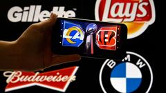 This illustration photo shows the logos of the Cincinnati Bengals and the Los Angeles Rams on a phone in front of the Gillette, Lays, Budweiser and BMW logos displayed on a screen, in Washington, DC, February 9, 2022. - Big brands that have in some cases sat out for years the TV advertising frenzy around the biggest US sporting event -- the Super Bowl -- are returning Sunday and spending big amid record ad prices.
It's been a bumpy couple years marked by pandemic-era restraint and political polarization, but the American football championship offers an increasingly unequalled viewership too big to pass up. (Photo by Olivier DOULIERY / AFP)