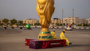 Soccer Football - FIFA World Cup Qatar 2022 Preview - Lusail, Qatar - November 10, 2022 Workers sit beside a replica of the World Cup outside Lusail Stadium ahead of the World Cup REUTERS/Marko Djurica