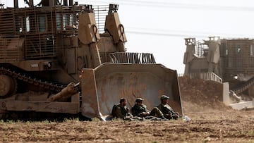 Israeli soldiers sit next to a heavy military bulldozer in an area near Israel's border with the Gaza Strip, in southern Israel October 19, 2023. REUTERS/Ronen Zvulun