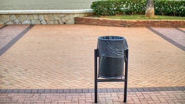 Black trash can in the city, in the background the beach