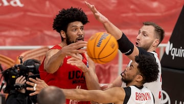 El ala pívot estadounidense de UCAM Murcia Kaiser Gates (c) pasa el balón a un compañero ante la presión del base de ERA NymburK Stephen Brown (2d), durante el partido octavos de final de la Liga de Campeones que se está disputando este miércoles en el Palacio de los Deportes de Murcia.