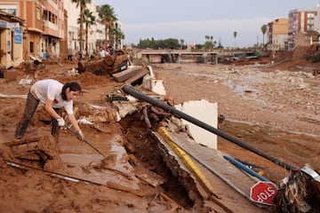 Una mujer barre el barro de la calle tras las fuertes lluvias que provocaron inundaciones, en Paiporta.