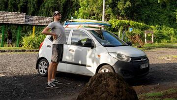 Un surfista estira al lado de su coche en el parking de un spot en Mahina, en el segundo día de flexibilización de las medidas contra el coronavirus que permiten surfear.