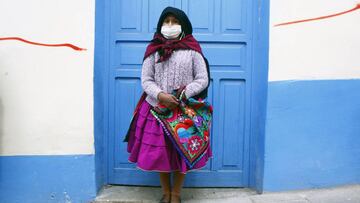 Maria Quispe, 21 wears a face mask while she queues in the highland city of Puno, close to the border with Bolivia, outside a bank on May 4, 2020 to collect the second bonus of 380 soles -about 107 US dollars- of governmental aid to help low income famili