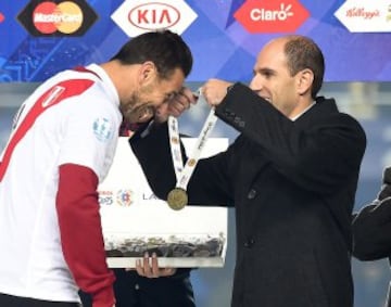 Peru's forward Claudio Pizarro (L) recevies a medal on the podium at the end of their Copa America third place football match against Paraguay in Concepcion, Chile on July 3, 2015. Peru won 2-0.  AFP PHOTO / LUIS ACOSTA