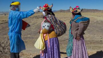 A health worker checks the temperature to residents from surrounding communities heading to the weekly food market in Coata, 40 km of Puno and close to the border with Bolivia on July 8, 2020. - The municipality of Coata has imposed mandatory disinfection and screening to all who visit the weekly fair, to avoid the the novel coronavirus from infecting the community as this remote district has not reported any COVID-19 cases. Peru ranks second in Latin America after Brazil with 312,911 cases, registering so far more than 11,000 deaths. (Photo by Carlos MAMANI / AFP)